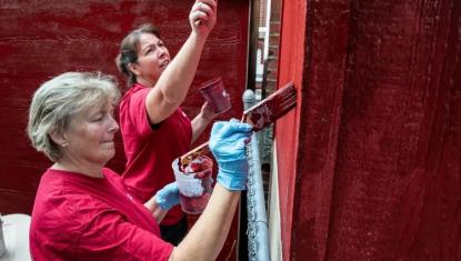 Volunteers painting a building red